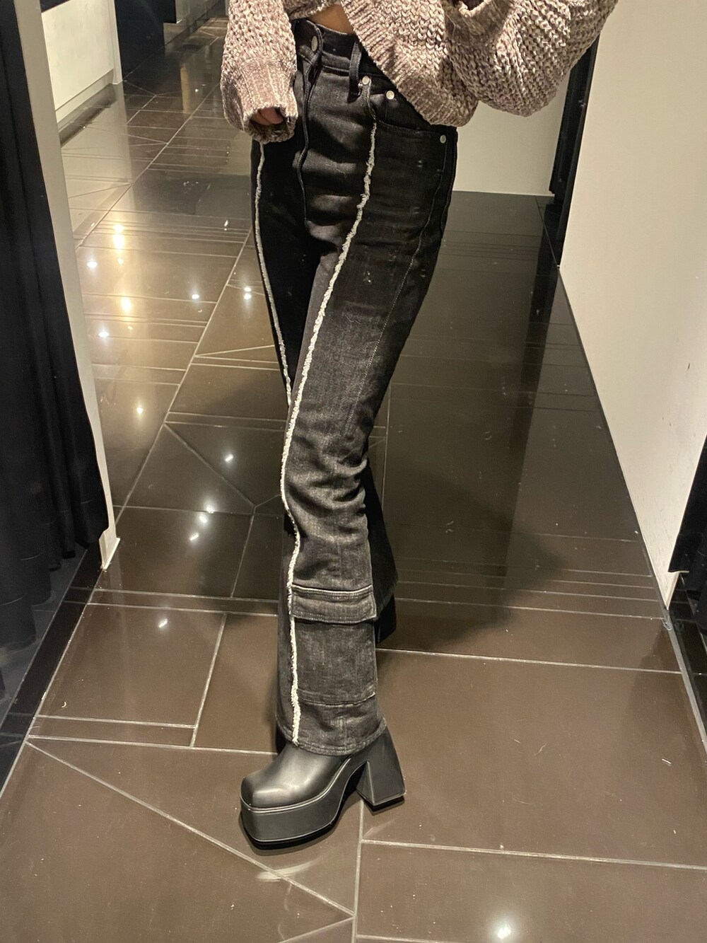 グレー系のニット/セーター、ブラック系のデニムパンツ、ブラック系のブーツを着用したレディースの秋コーディネートの5枚目の写真