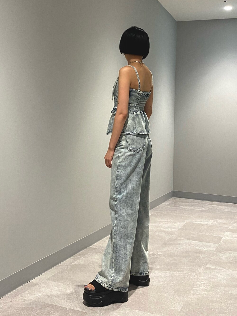 ブラック系のサンダル、ブルー系のデニムパンツ、ブルー系のキャミソールを着用したレディースの夏コーディネートの3枚目の写真