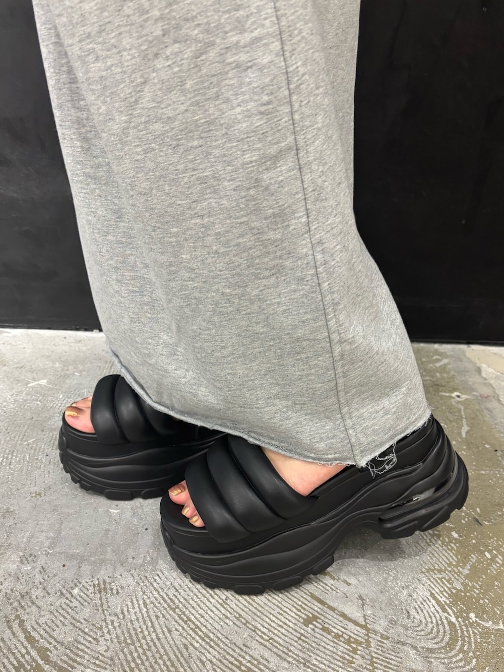 ブラック系のTシャツ/カットソー、グレー系のスカート、ブラック系のサンダルを着用したレディースの夏コーディネートの6枚目の写真