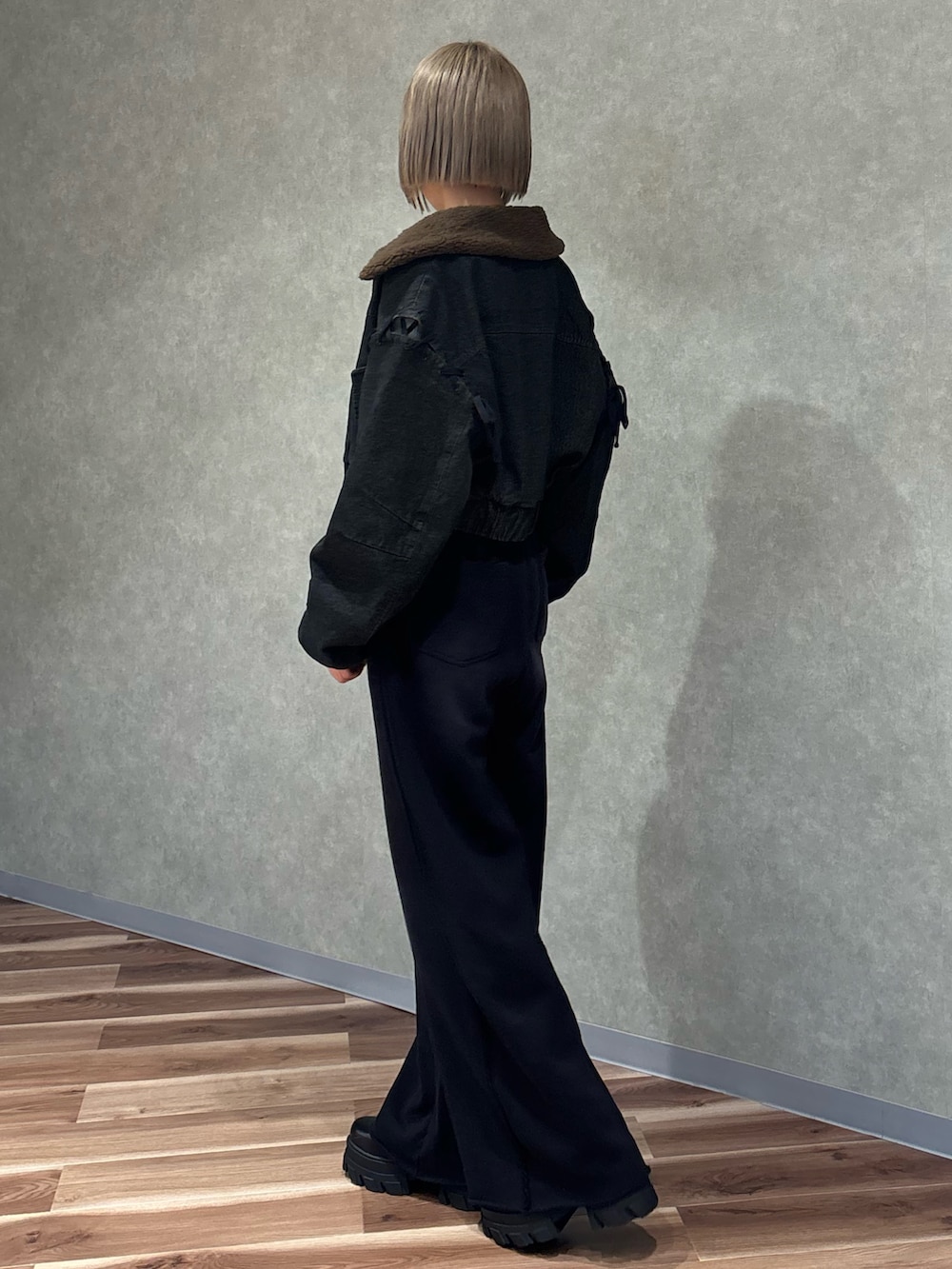 ブラック系のブーツ、ブラック系のブルゾン、ホワイト系のニット/セーターを着用したレディースの秋コーディネートの2枚目の写真