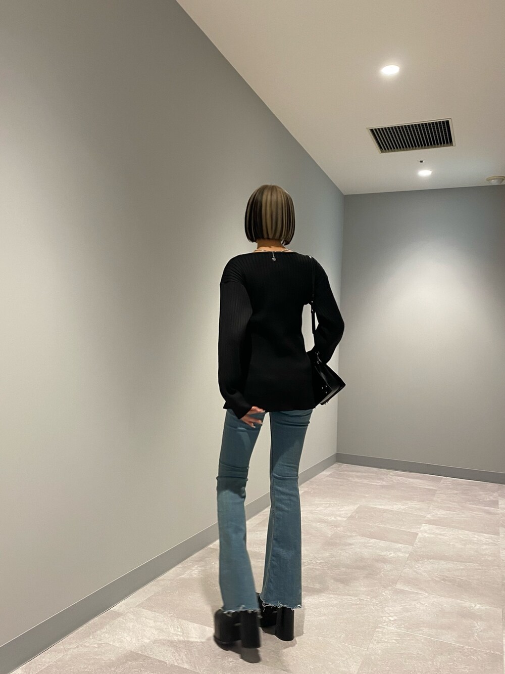 ブルー系のデニムパンツ、ブラック系のショルダーバッグ、ブラック系のブーツを着用したレディースの冬コーディネートの3枚目の写真