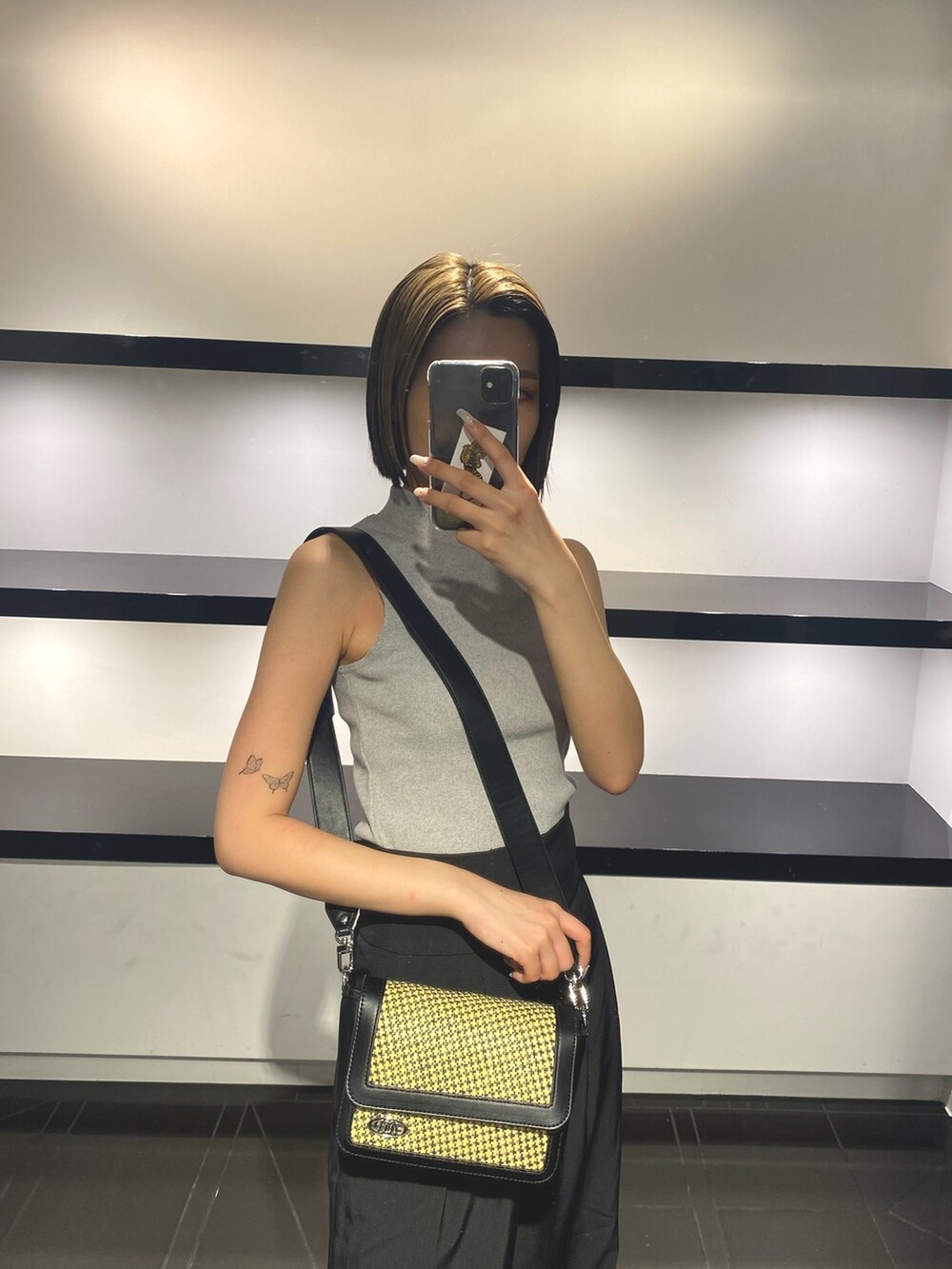 グレー系のタンクトップ、ベージュ系のショルダーバッグ、ブラック系のその他パンツを着用したレディースの夏コーディネートの4枚目の写真