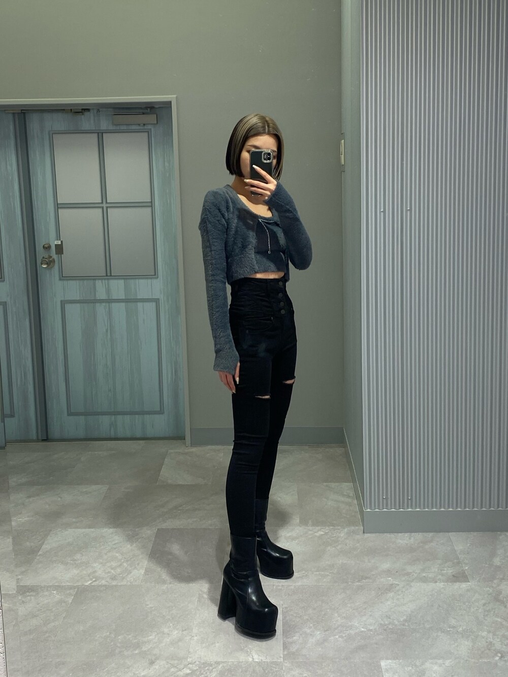 ブラック系のデニムパンツ、ブラック系のブーツ、グレー系のニット/セーターを着用したレディースの冬コーディネートの2枚目の写真