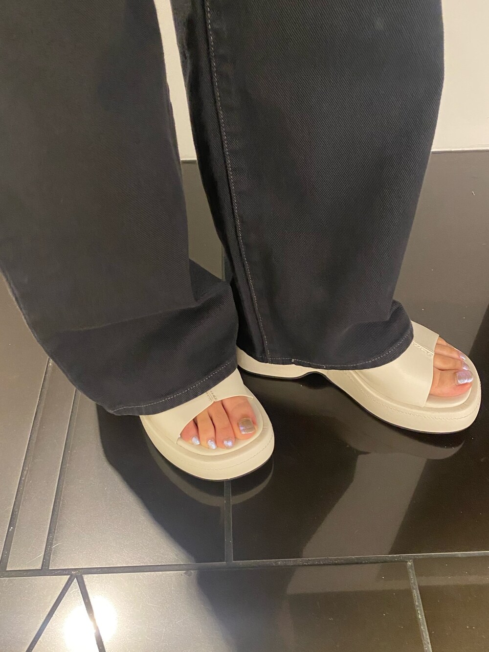 ブラック系のデニムパンツ、ホワイト系のサンダル、ブラック系のタンクトップを着用したレディースの春コーディネートの5枚目の写真