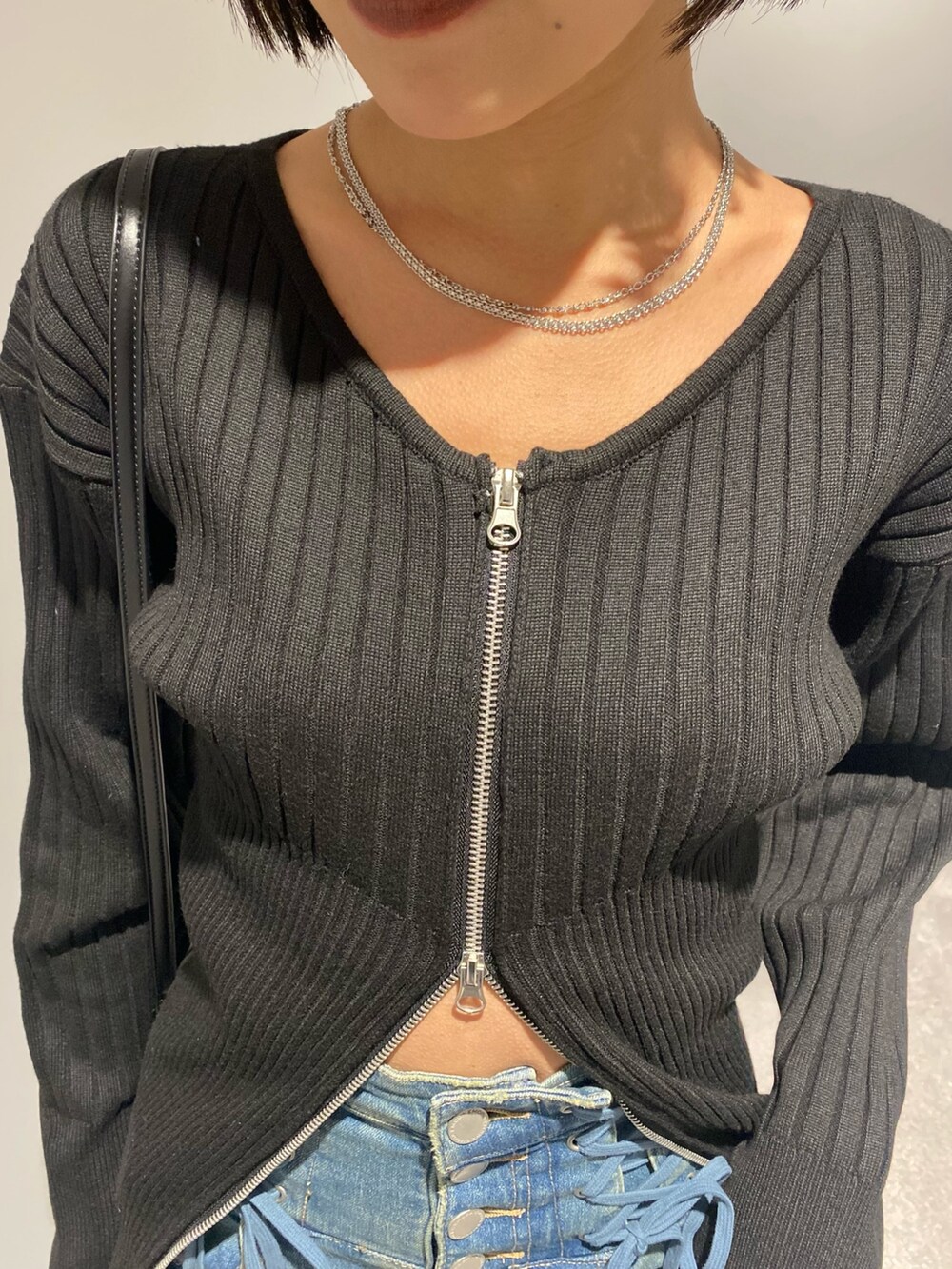 ブルー系のデニムパンツ、ブラック系のショルダーバッグ、ブラック系のブーツを着用したレディースの冬コーディネートの5枚目の写真