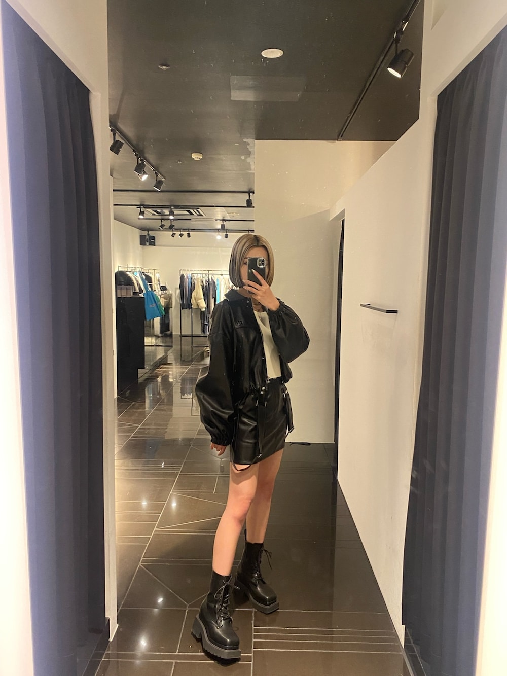 ブラック系のブーツ、ブラック系のスカート、ホワイト系のニット/セーターを着用したレディースの冬コーディネートの2枚目の写真