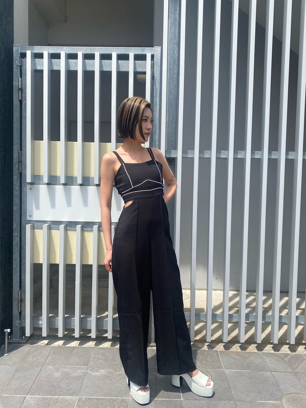 ブラック系のサロペット/オーバーオール、ホワイト系のサンダルを着用したレディースの夏コーディネートの2枚目の写真