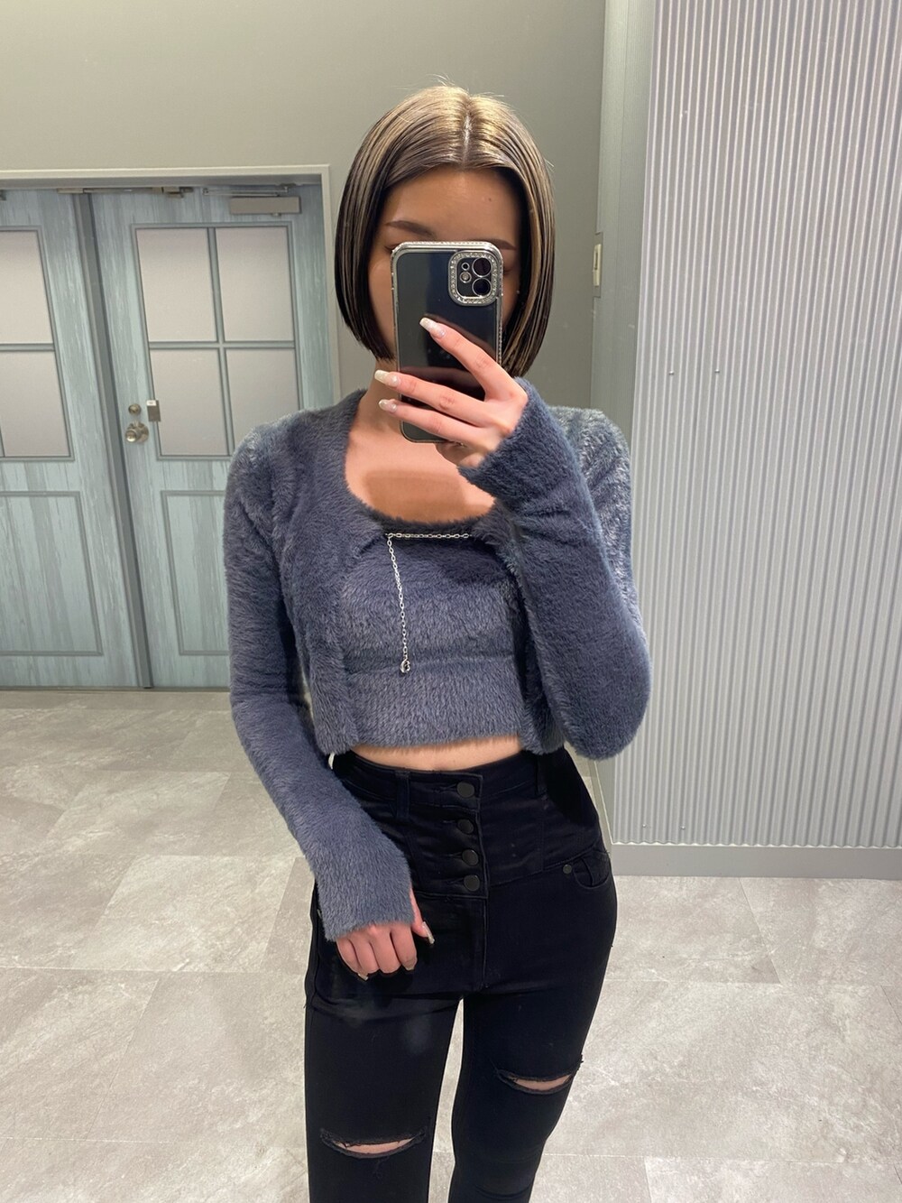 ブラック系のデニムパンツ、ブラック系のブーツ、グレー系のニット/セーターを着用したレディースの冬コーディネートの3枚目の写真