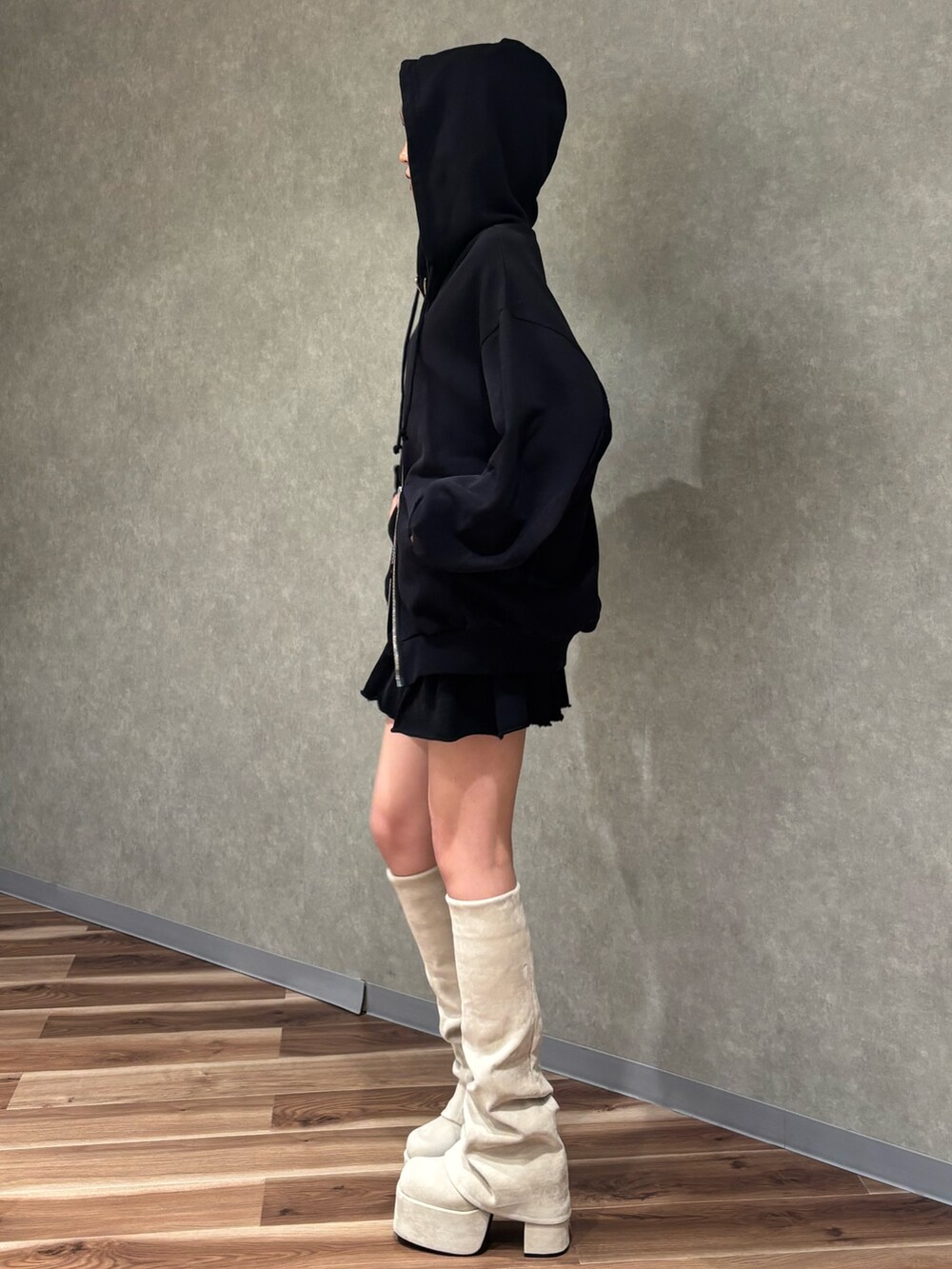 ホワイト系のブーツ、ブラック系のスカート、ブラック系のパーカーを着用したレディースの秋コーディネートの2枚目の写真