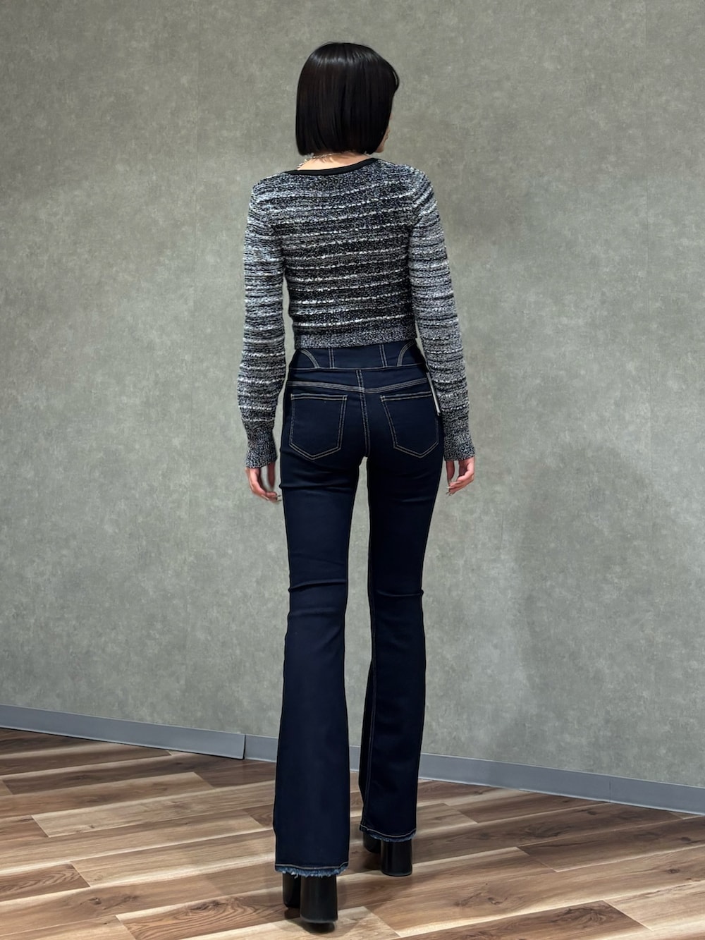 ブルー系のデニムパンツ、ブラック系のニット/セーター、ブラック系のブーツを着用したレディースの冬コーディネートの3枚目の写真