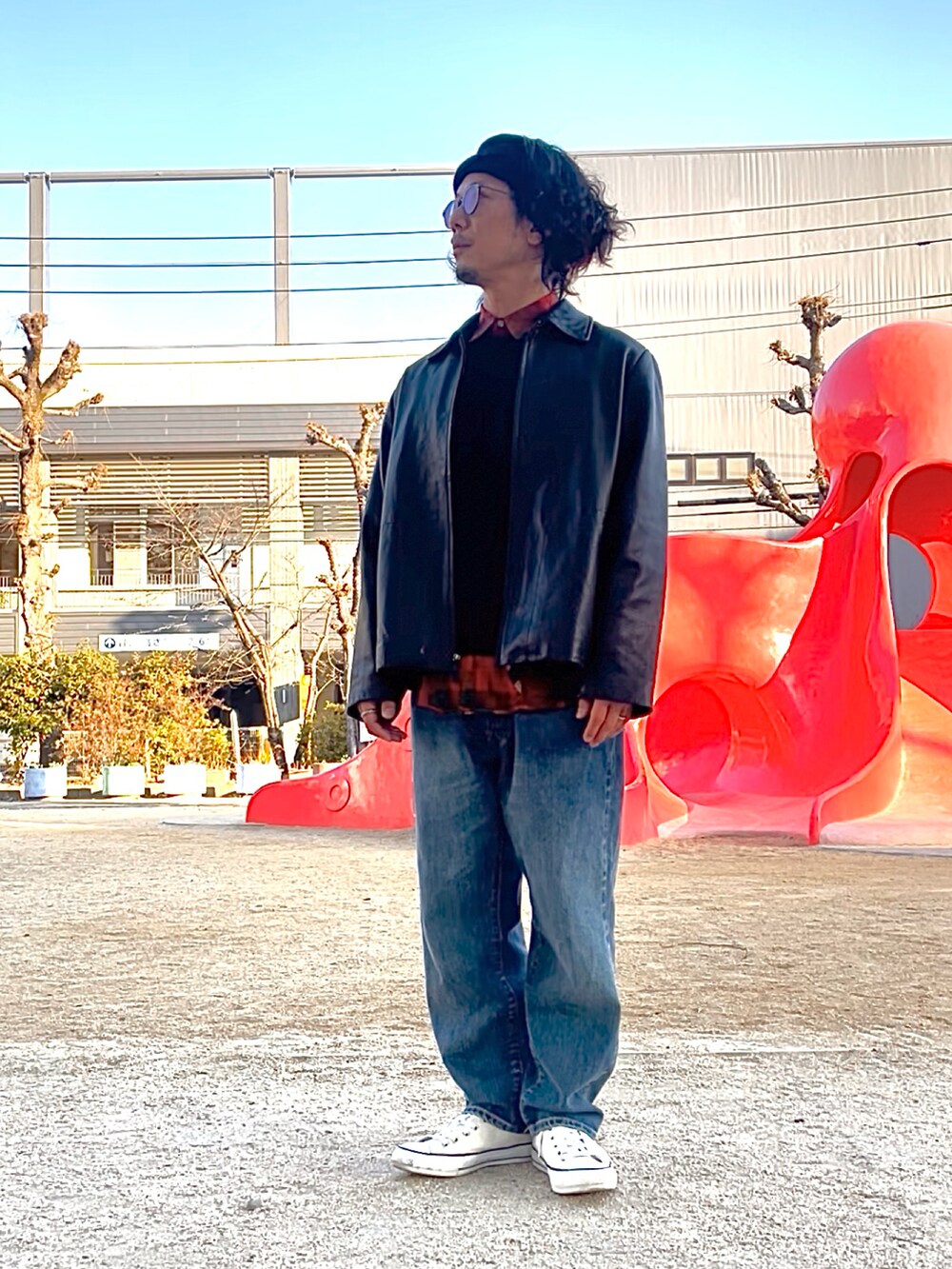 ブルー系のデニムパンツ、ホワイト系のスニーカー、ブラック系のライダースジャケットを着用したメンズの冬コーディネートの2枚目の写真