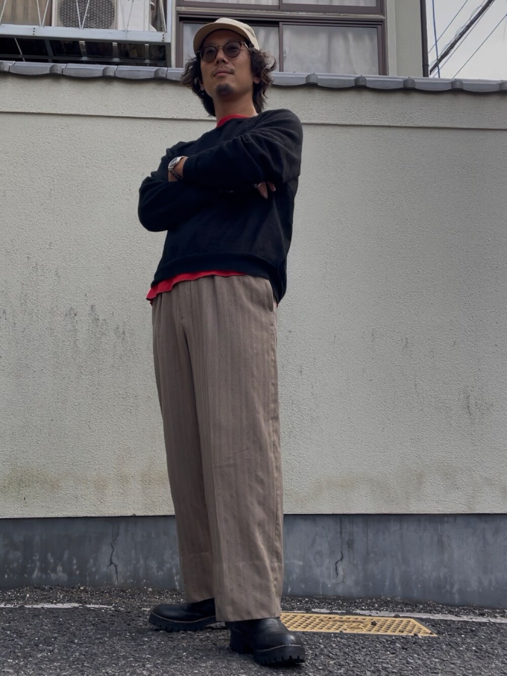 ブラック系のニット/セーター、ベージュ系のスラックス、ブラック系のブーツを着用したメンズの秋コーディネートの2枚目の写真