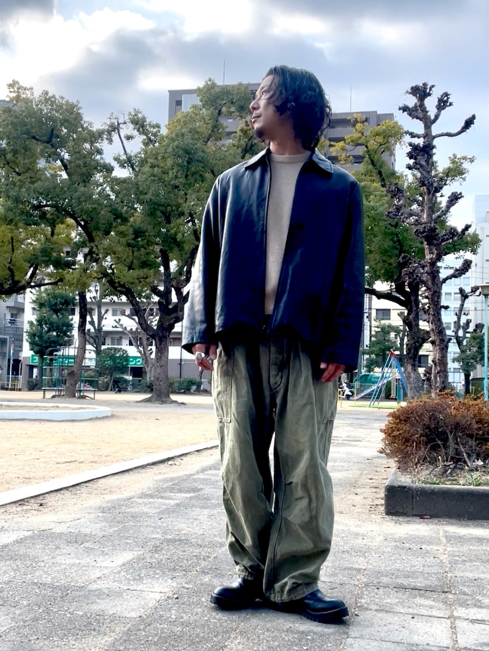 ベージュ系のニット/セーター、ブラック系のライダースジャケット、グリーン系のカーゴパンツを着用したメンズの冬コーディネートの2枚目の写真