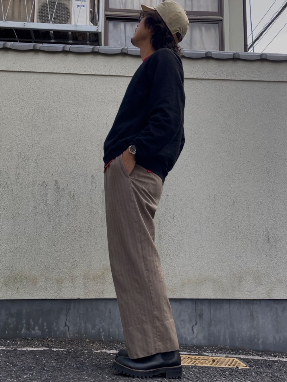 ブラック系のニット/セーター、ベージュ系のスラックス、ブラック系のブーツを着用したメンズの秋コーディネートの3枚目の写真