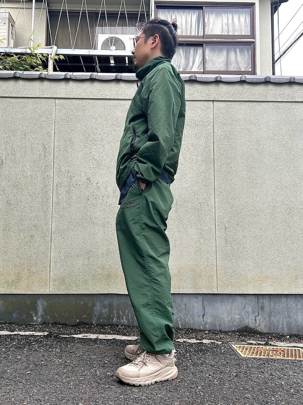 グリーン系のその他パンツ、グリーン系のナイロンジャケット、ブルー系のシャツ/ブラウスを着用したメンズの春コーディネートの2枚目の写真
