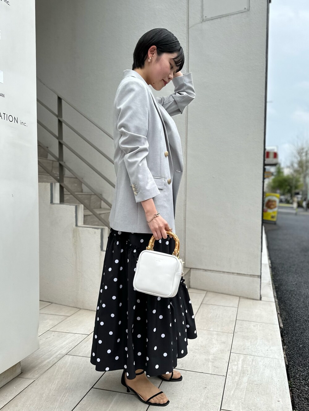 グレー系のテーラードジャケット、ホワイト系のTシャツ/カットソー、ブラック系のスカートを着用したレディースの春コーディネートの3枚目の写真