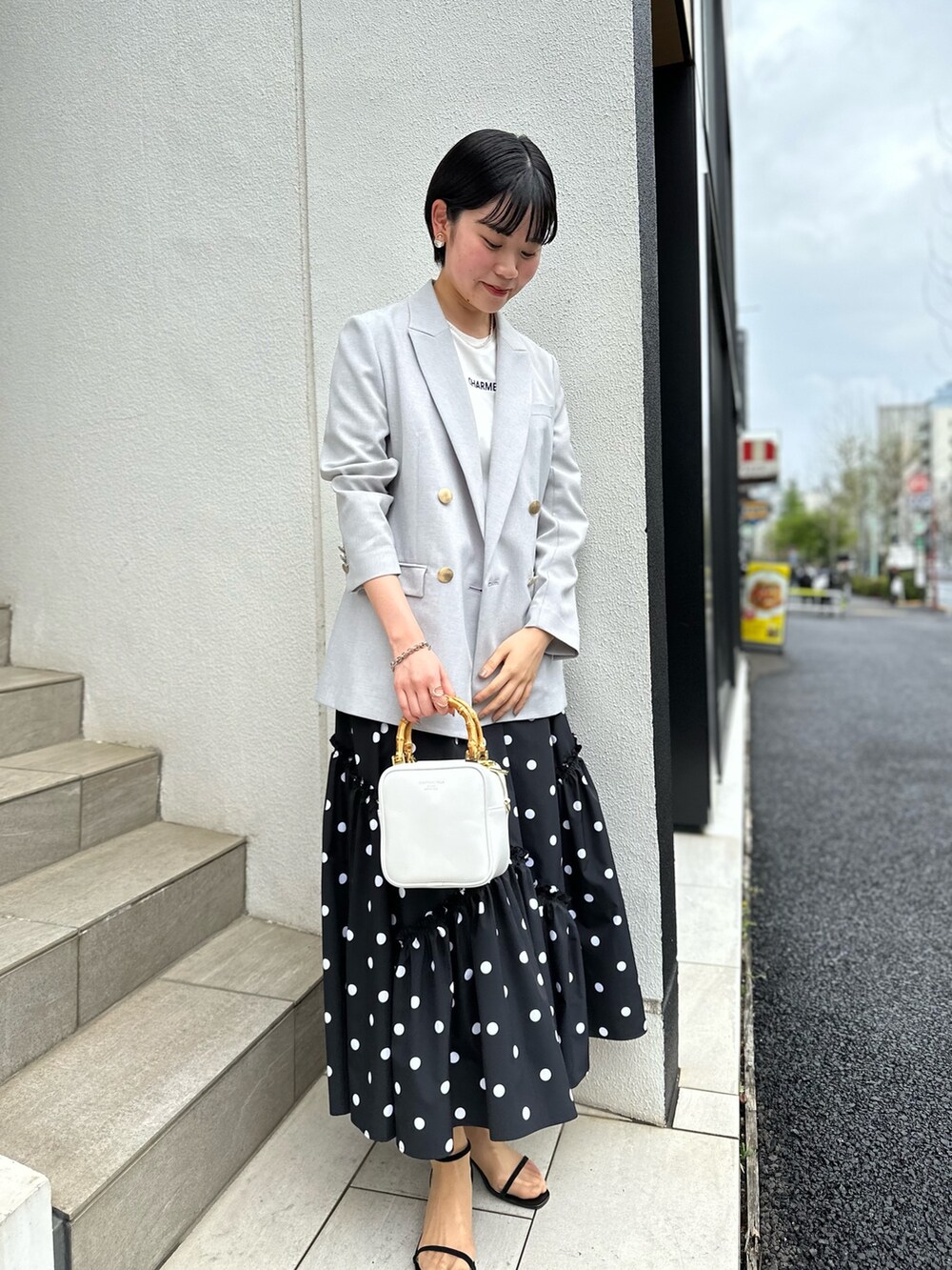グレー系のテーラードジャケット、ホワイト系のTシャツ/カットソー、ブラック系のスカートを着用したレディースの春コーディネートの5枚目の写真