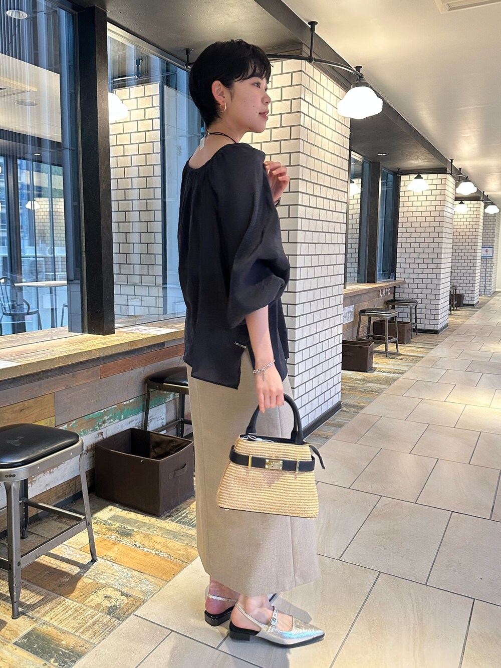 ブラック系のシャツ/ブラウス、ベージュ系のスカート、ブラック系のかごバッグを着用したレディースの春コーディネートの3枚目の写真