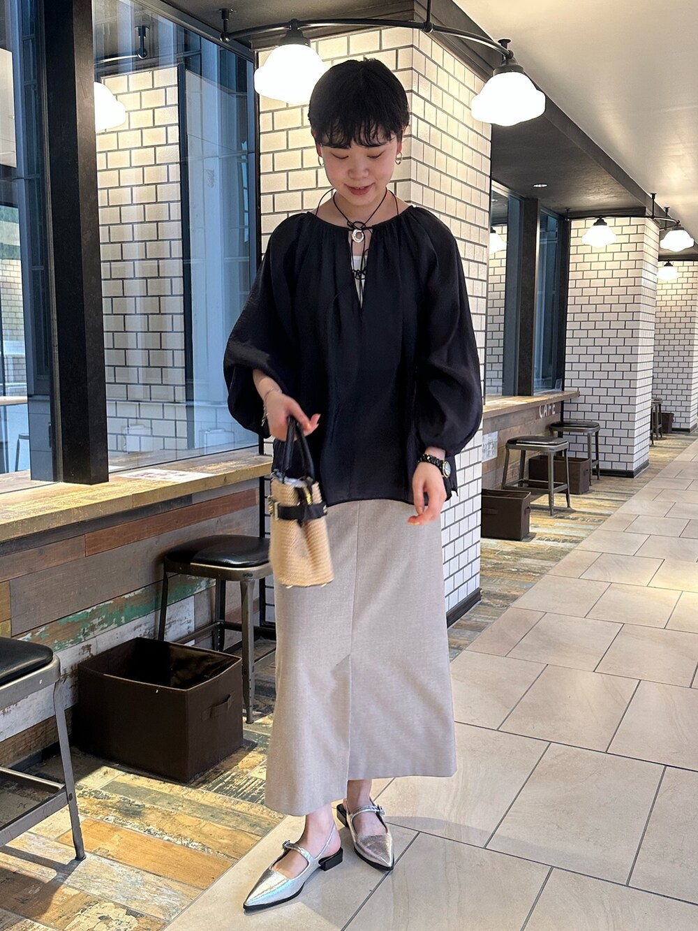 ブラック系のシャツ/ブラウス、ベージュ系のスカート、ブラック系のかごバッグを着用したレディースの春コーディネートの2枚目の写真