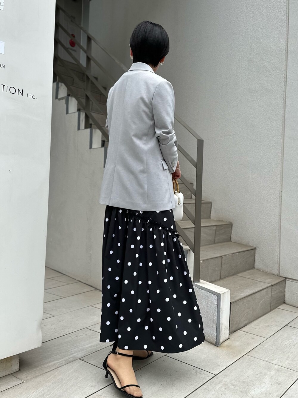 グレー系のテーラードジャケット、ホワイト系のTシャツ/カットソー、ブラック系のスカートを着用したレディースの春コーディネートの4枚目の写真