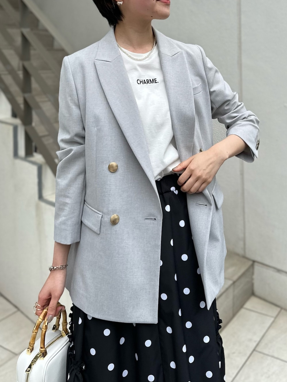 グレー系のテーラードジャケット、ホワイト系のTシャツ/カットソー、ブラック系のスカートを着用したレディースの春コーディネートの6枚目の写真