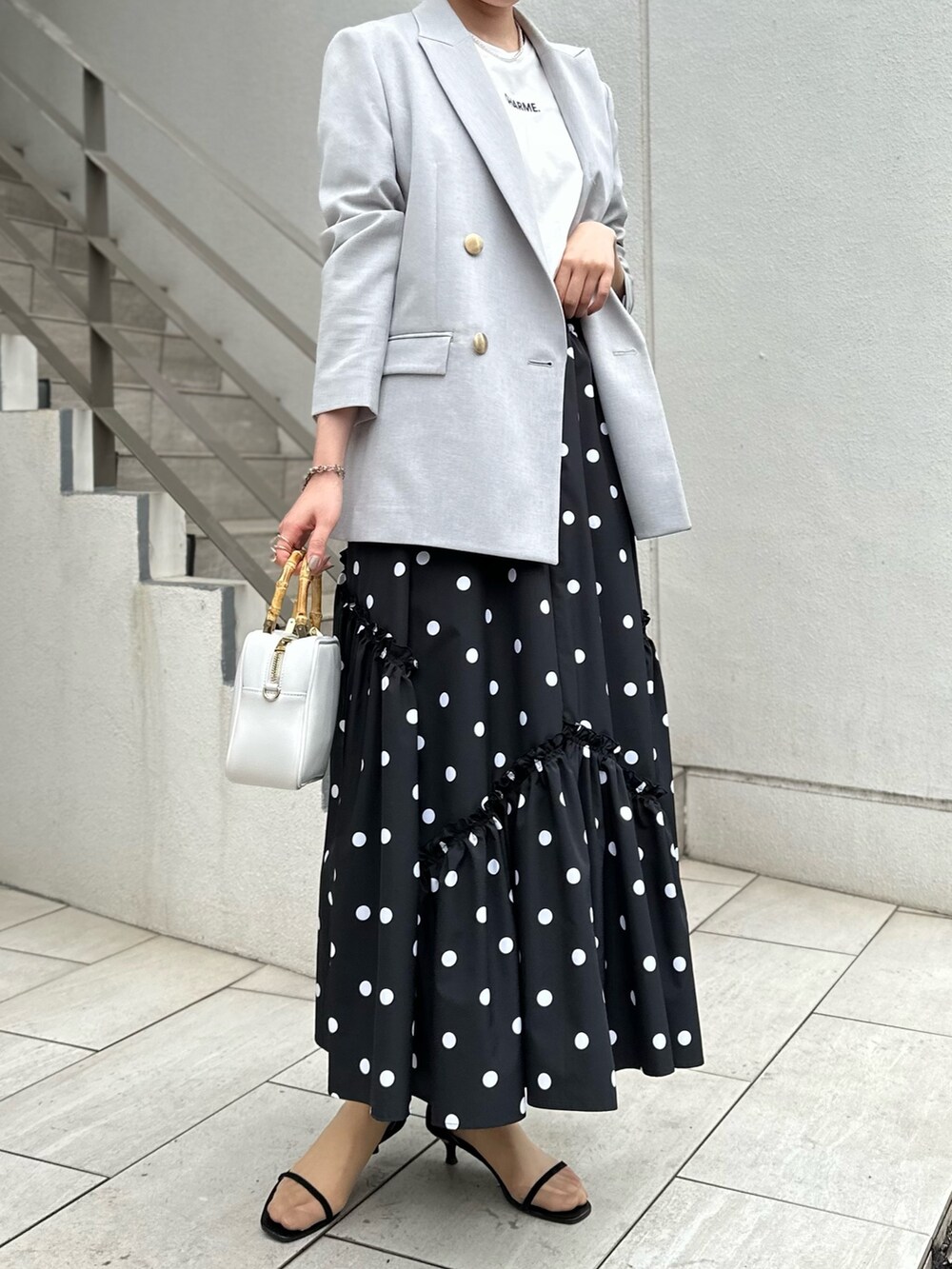 グレー系のテーラードジャケット、ホワイト系のTシャツ/カットソー、ブラック系のスカートを着用したレディースの春コーディネートの7枚目の写真