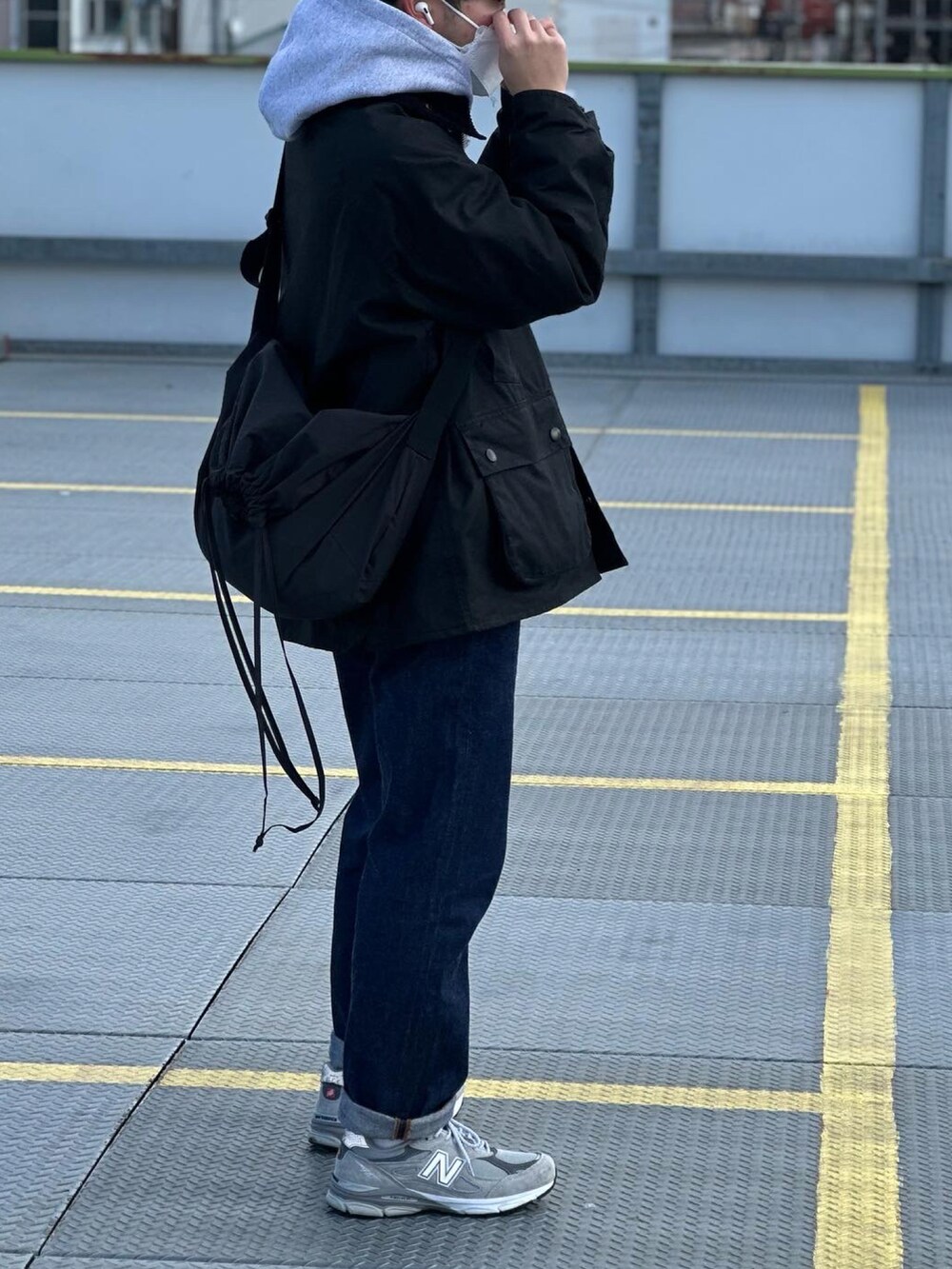 ブルー系のデニムパンツ、ブラック系のミリタリージャケット、ブラック系のショルダーバッグを着用したメンズの冬コーディネートの2枚目の写真