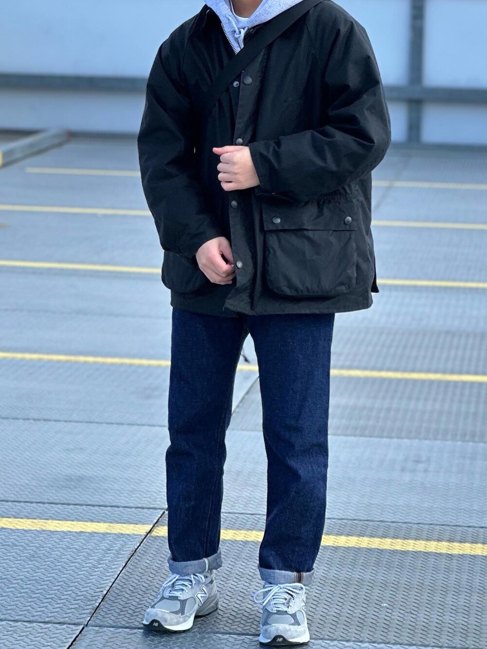 ブルー系のデニムパンツ、ブラック系のミリタリージャケット、ブラック系のショルダーバッグを着用したメンズの冬コーディネートの4枚目の写真