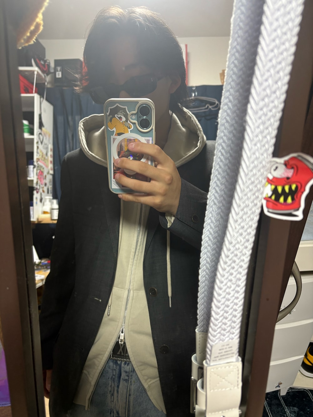 グレー系のテーラードジャケット、ベージュ系のパーカー、ブルー系のデニムパンツを着用したメンズの夏コーディネートの2枚目の写真