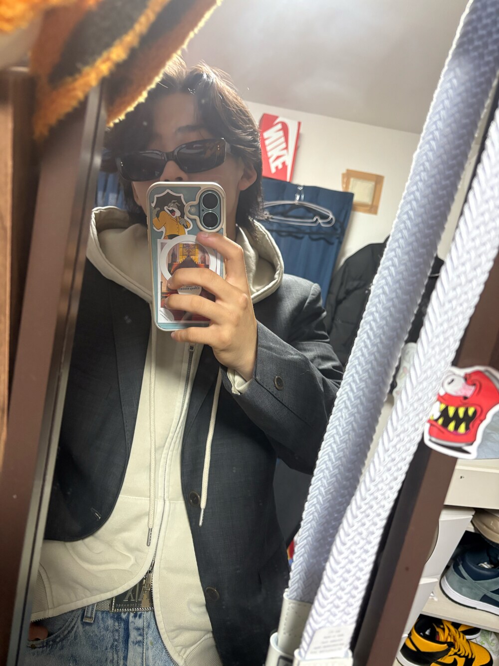 グレー系のテーラードジャケット、ベージュ系のパーカー、ブルー系のデニムパンツを着用したメンズの夏コーディネートの3枚目の写真