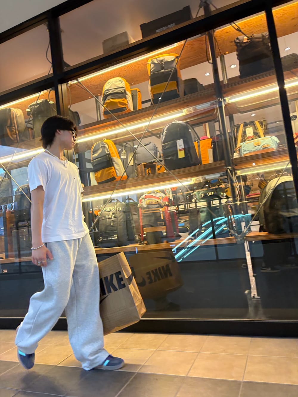 グレー系のスウェットパンツ、ブルー系のスニーカー、ホワイト系のTシャツ/カットソーを着用したメンズの夏コーディネートの2枚目の写真