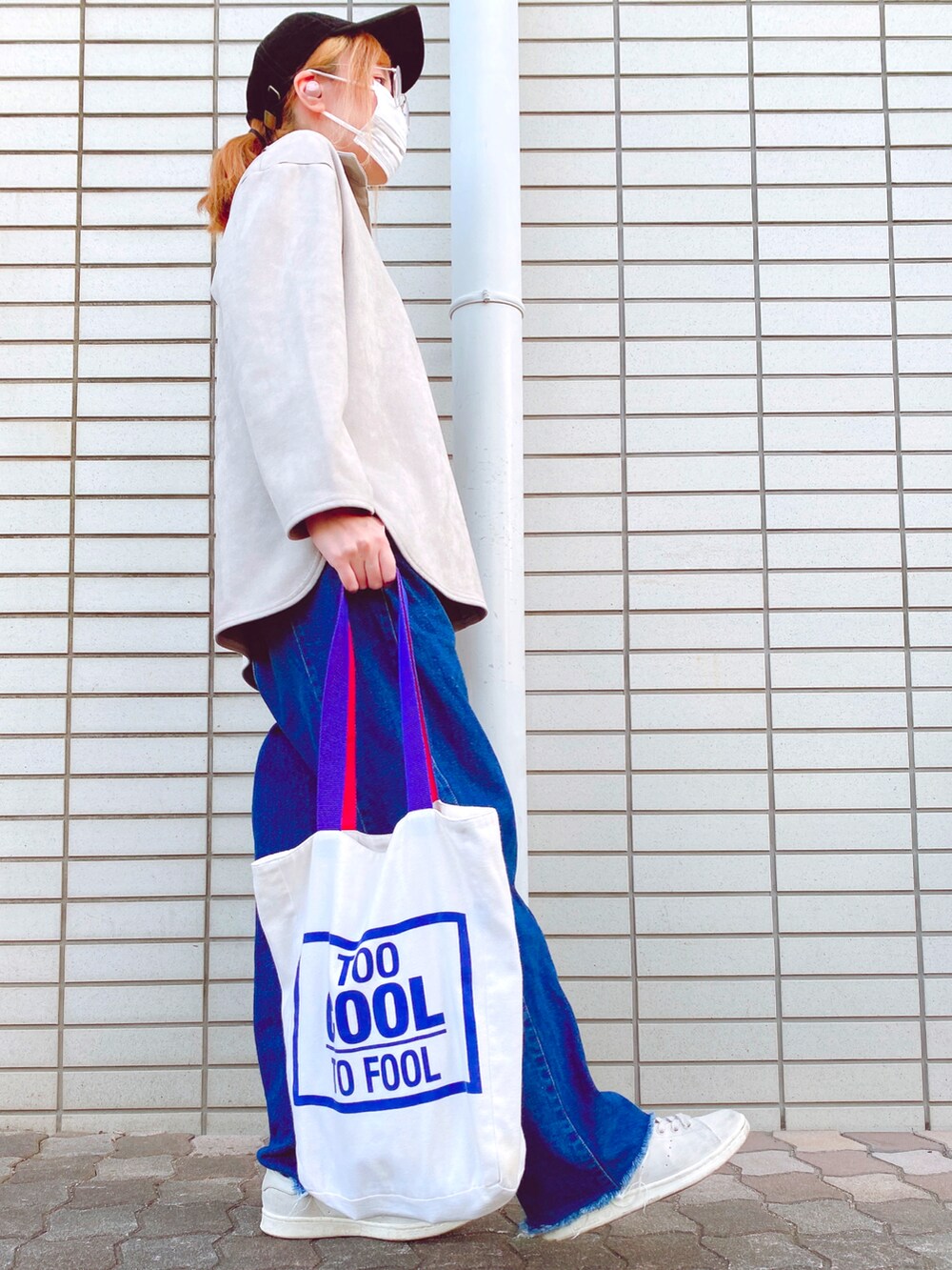 グレー系のトップス、ブルー系のデニムパンツ、ベージュ系のスニーカーを着用したレディースの春コーディネートの3枚目の写真