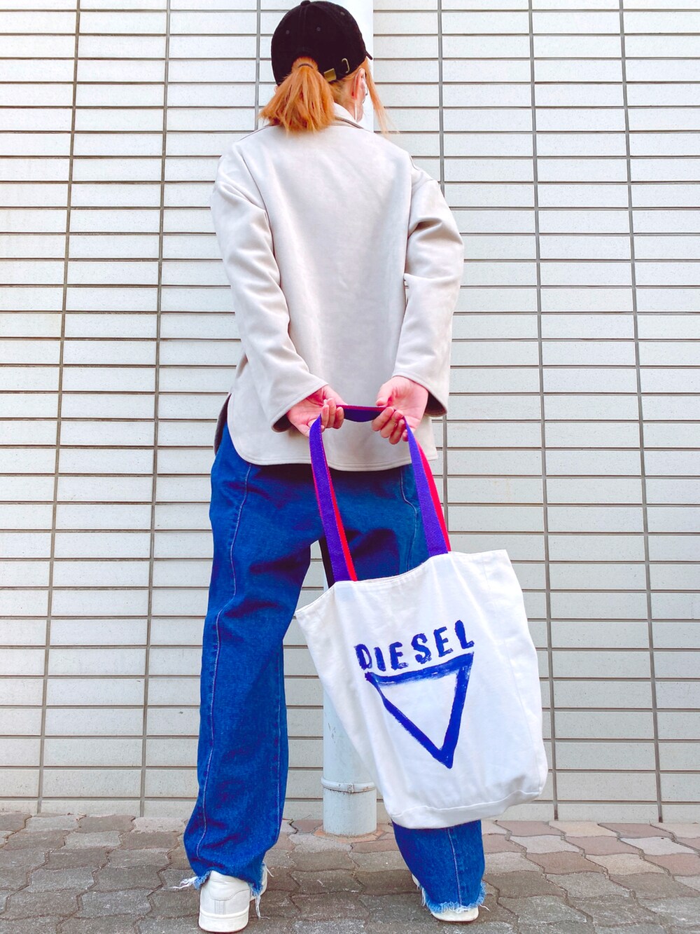 グレー系のトップス、ブルー系のデニムパンツ、ベージュ系のスニーカーを着用したレディースの春コーディネートの2枚目の写真