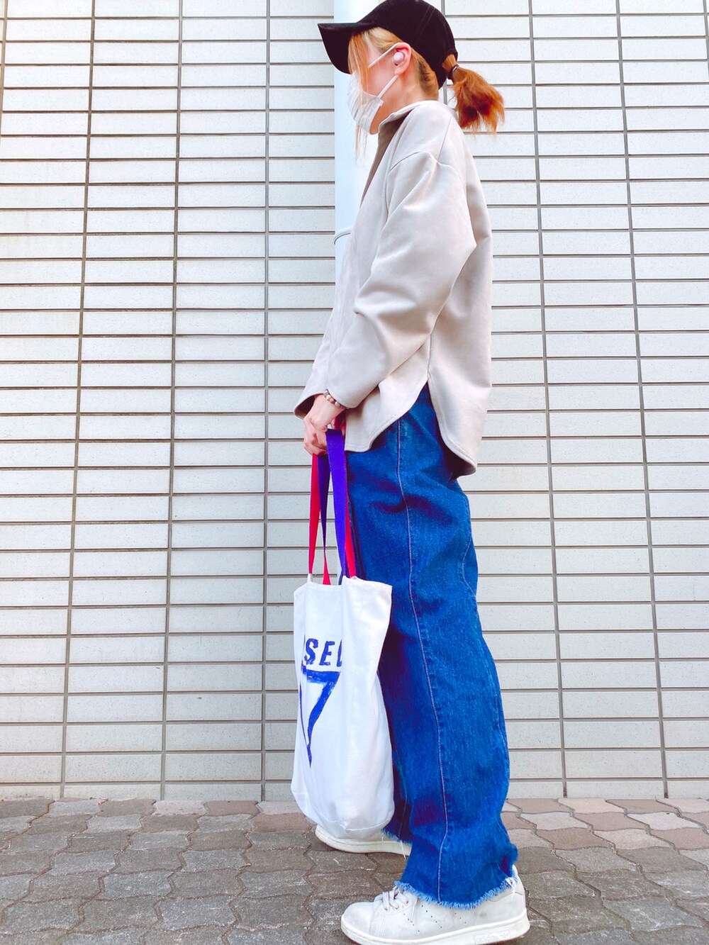 グレー系のトップス、ブルー系のデニムパンツ、ベージュ系のスニーカーを着用したレディースの春コーディネートの4枚目の写真