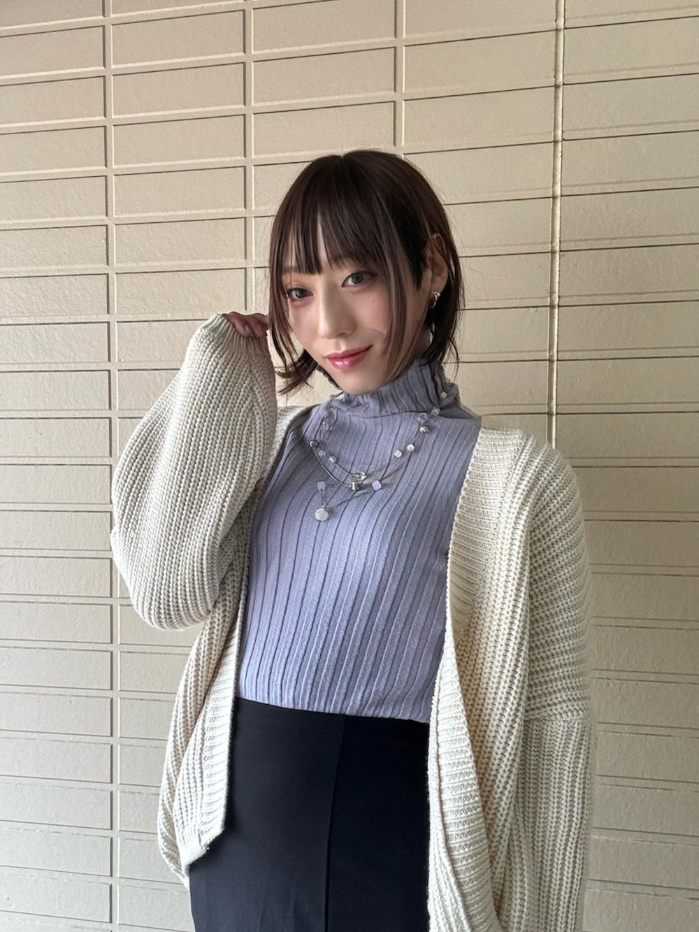 パープル系のニット/セーター、ブラック系のスカートを着用したレディースの冬コーディネートの2枚目の写真