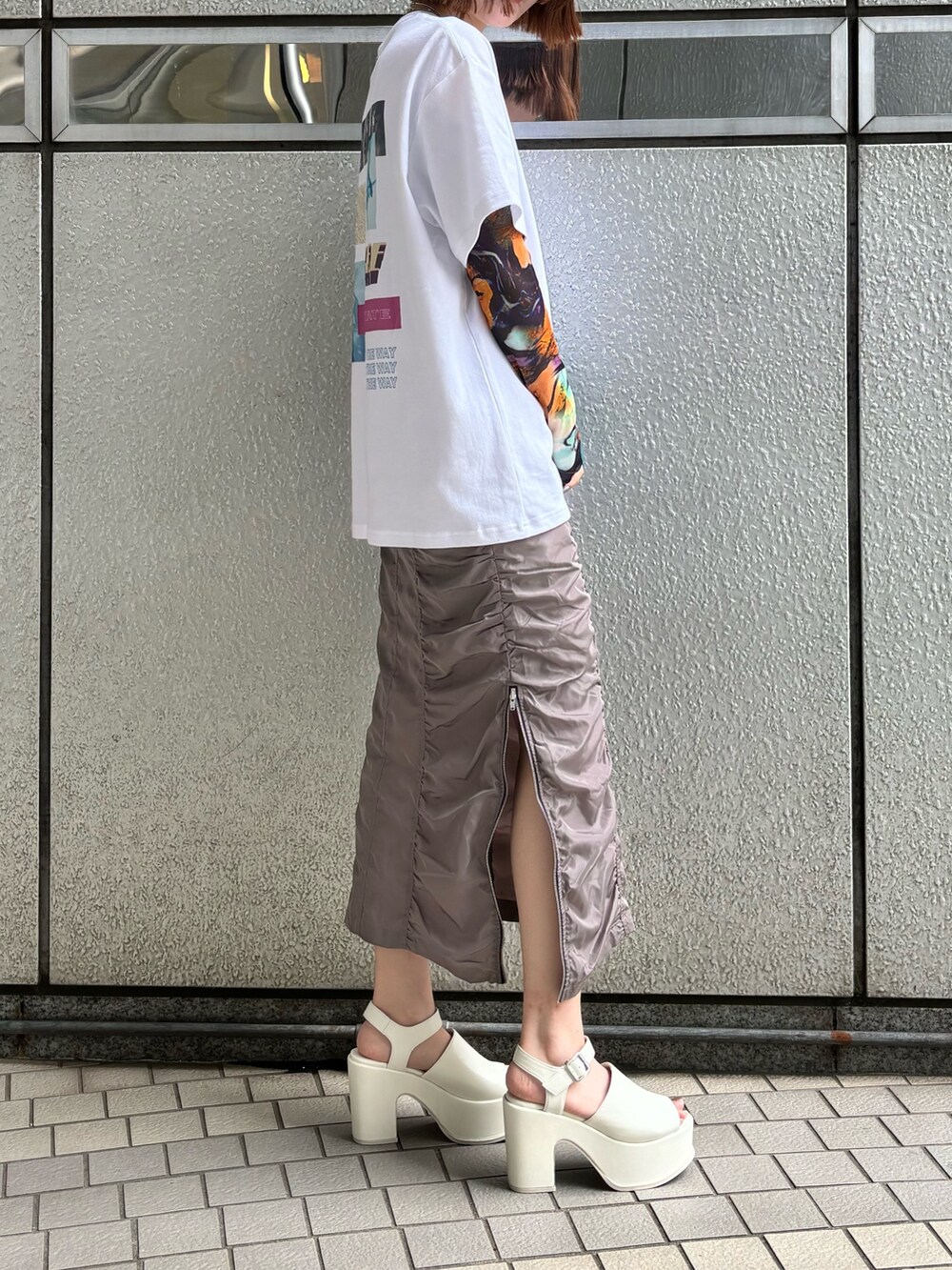 グレー系のスカート、ホワイト系のTシャツ/カットソー、ゴールド系のネックレスを着用したレディースの春コーディネートの2枚目の写真