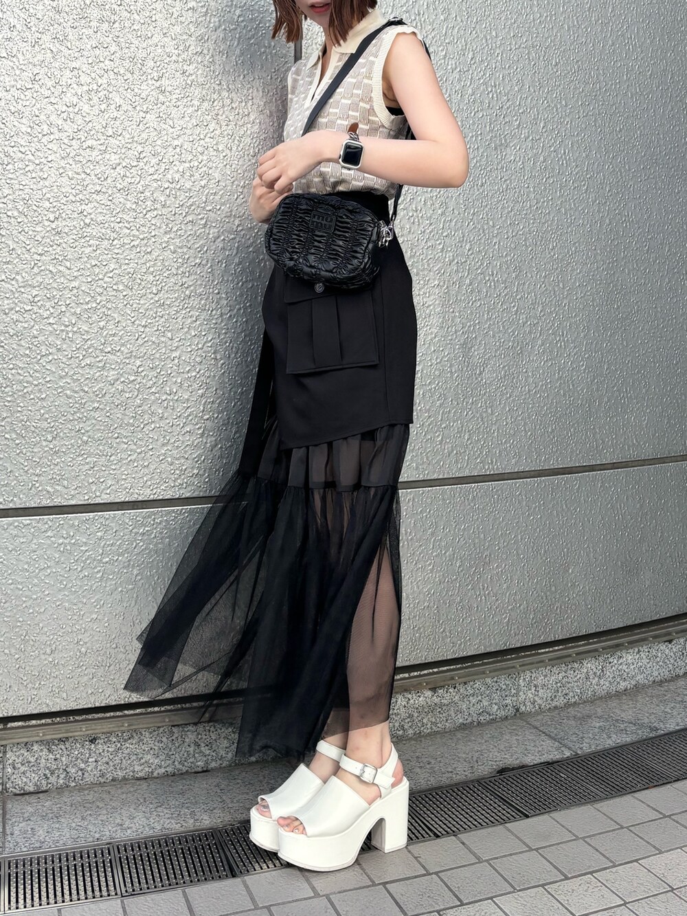 ブラック系のスカート、ブラック系のショルダーバッグ、ホワイト系のニット/セーターを着用したレディースの春コーディネートの2枚目の写真