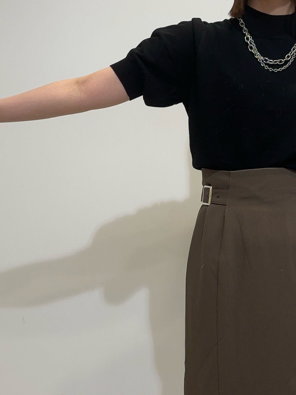 ブラウン系のスカート、ホワイト系のムートンコート、ブラウン系のブーツを着用したレディースの夏コーディネートの7枚目の写真