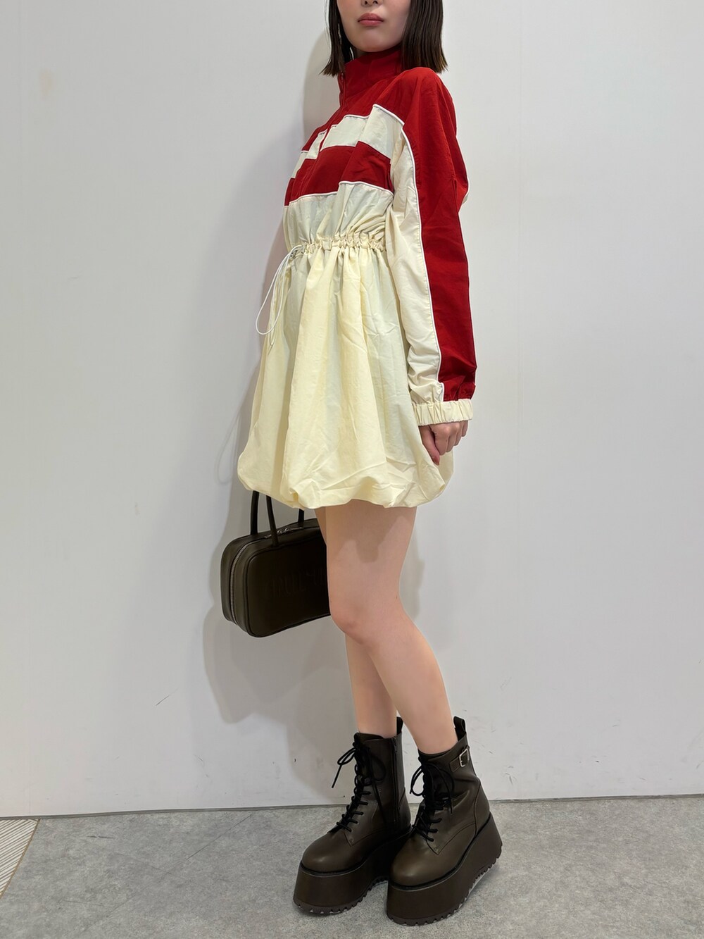 レッド系のワンピース、ブラウン系のブーツ、ブラウン系のボストンバッグを着用したレディースの夏コーディネートの3枚目の写真