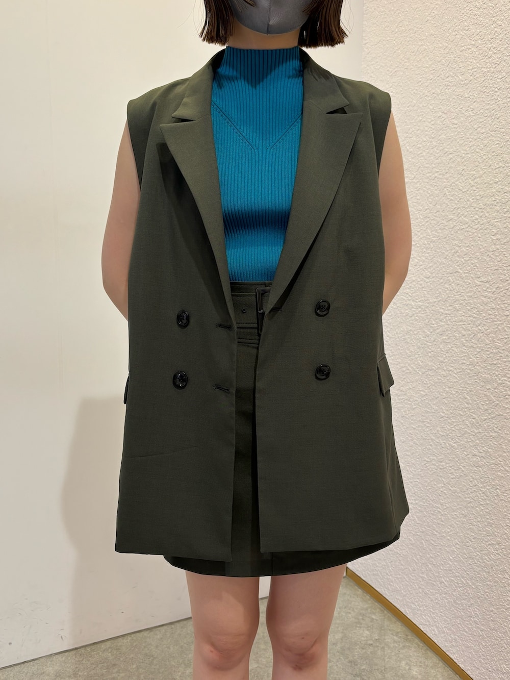 グレー系のベスト、グレー系のスカート、ブラック系のブーツを着用したレディースの春コーディネートの3枚目の写真