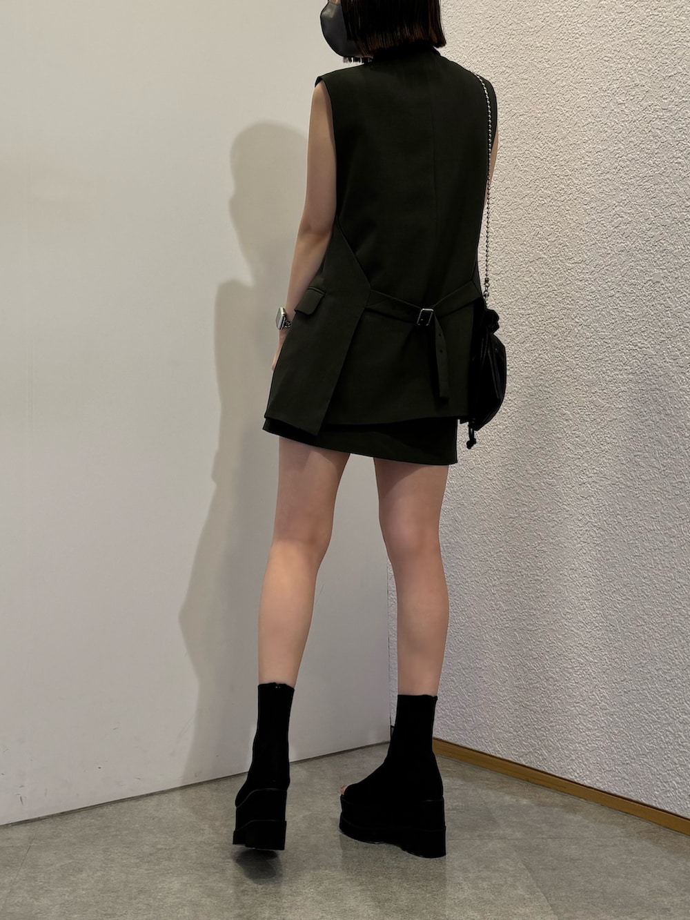 グレー系のベスト、グレー系のスカート、ブラック系のブーツを着用したレディースの春コーディネートの2枚目の写真