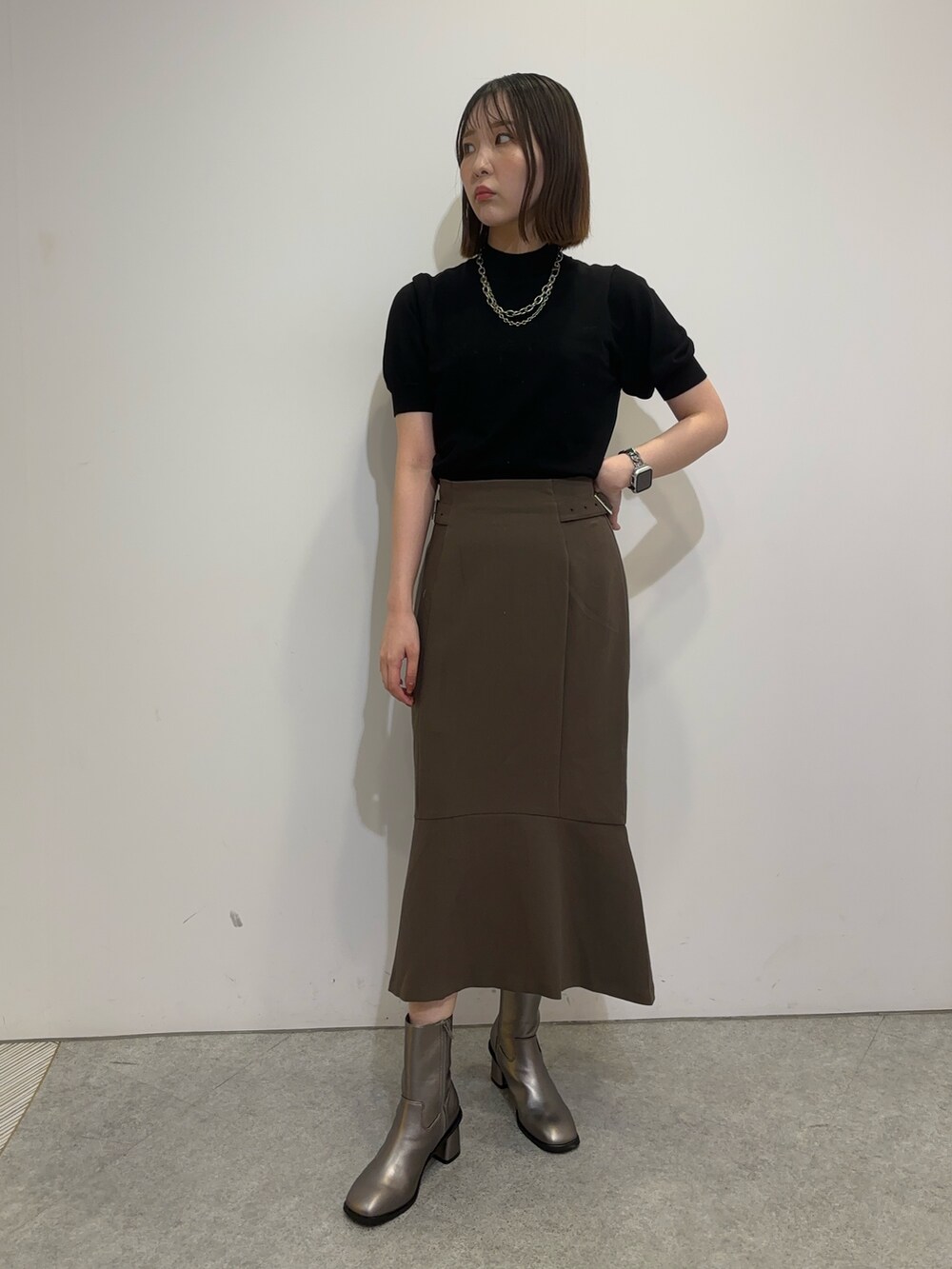 ブラウン系のスカート、ホワイト系のムートンコート、ブラウン系のブーツを着用したレディースの夏コーディネートの5枚目の写真