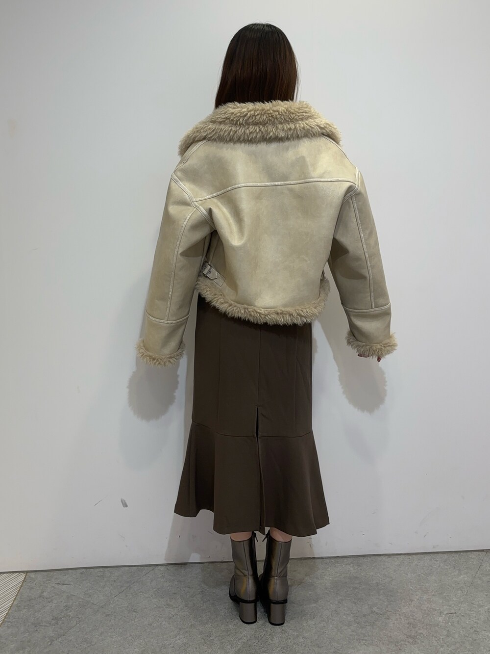 ブラウン系のスカート、ホワイト系のムートンコート、ブラウン系のブーツを着用したレディースの夏コーディネートの4枚目の写真