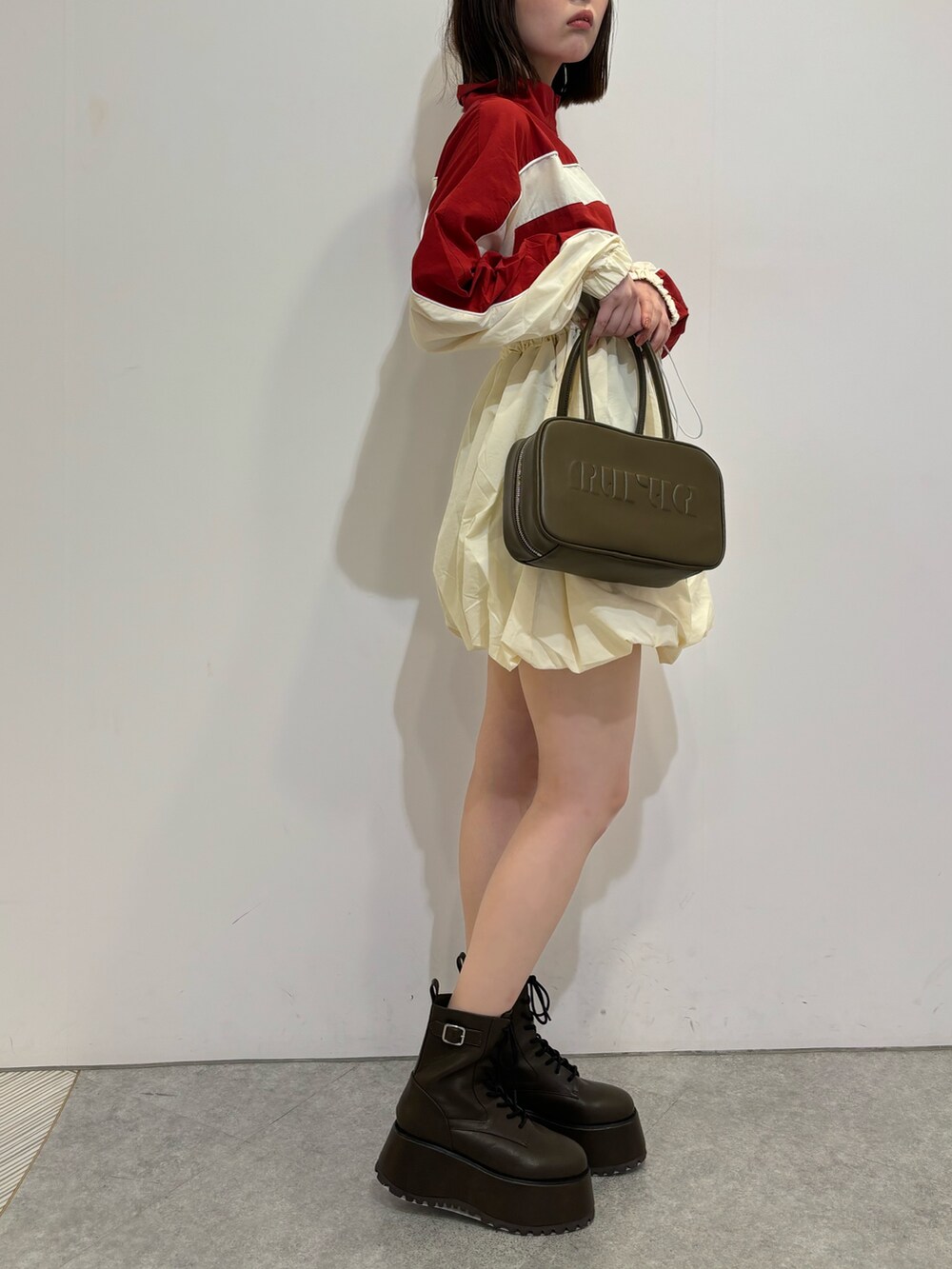 レッド系のワンピース、ブラウン系のブーツ、ブラウン系のボストンバッグを着用したレディースの夏コーディネートの2枚目の写真