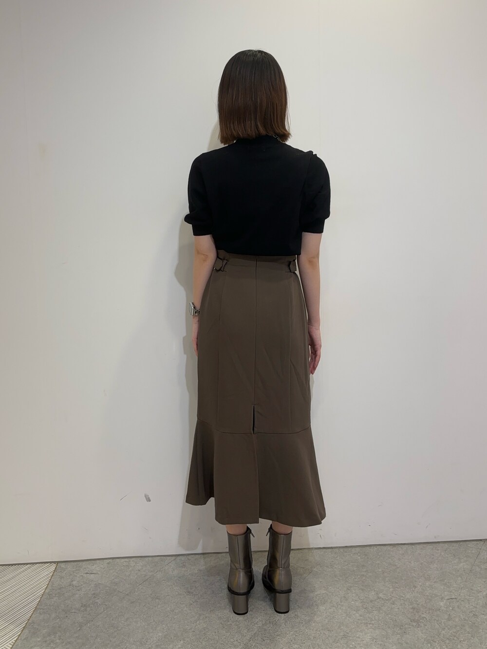 ブラウン系のスカート、ホワイト系のムートンコート、ブラウン系のブーツを着用したレディースの夏コーディネートの6枚目の写真