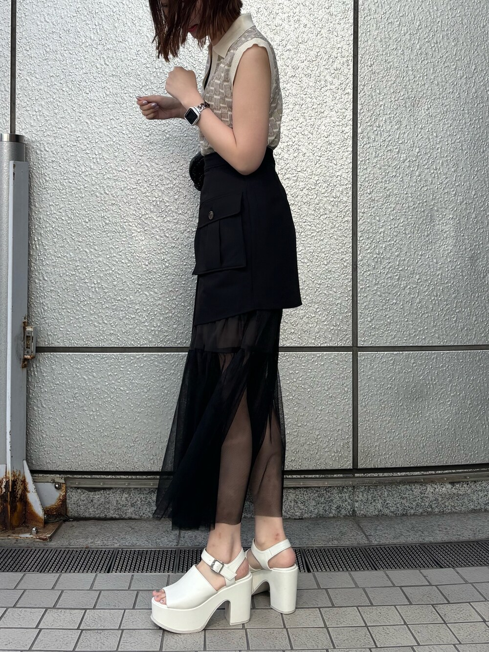 ブラック系のスカート、ブラック系のショルダーバッグ、ホワイト系のニット/セーターを着用したレディースの春コーディネートの5枚目の写真