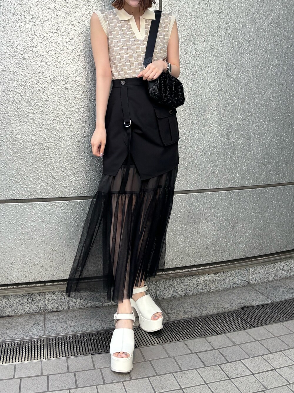 ブラック系のスカート、ブラック系のショルダーバッグ、ホワイト系のニット/セーターを着用したレディースの春コーディネートの3枚目の写真