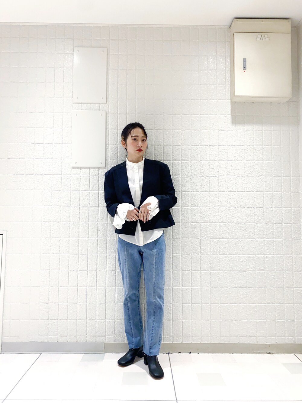 ブラック系のチェスターコート、ホワイト系のシャツ/ブラウス、ブルー系のデニムパンツを着用したレディースの冬コーディネートの2枚目の写真