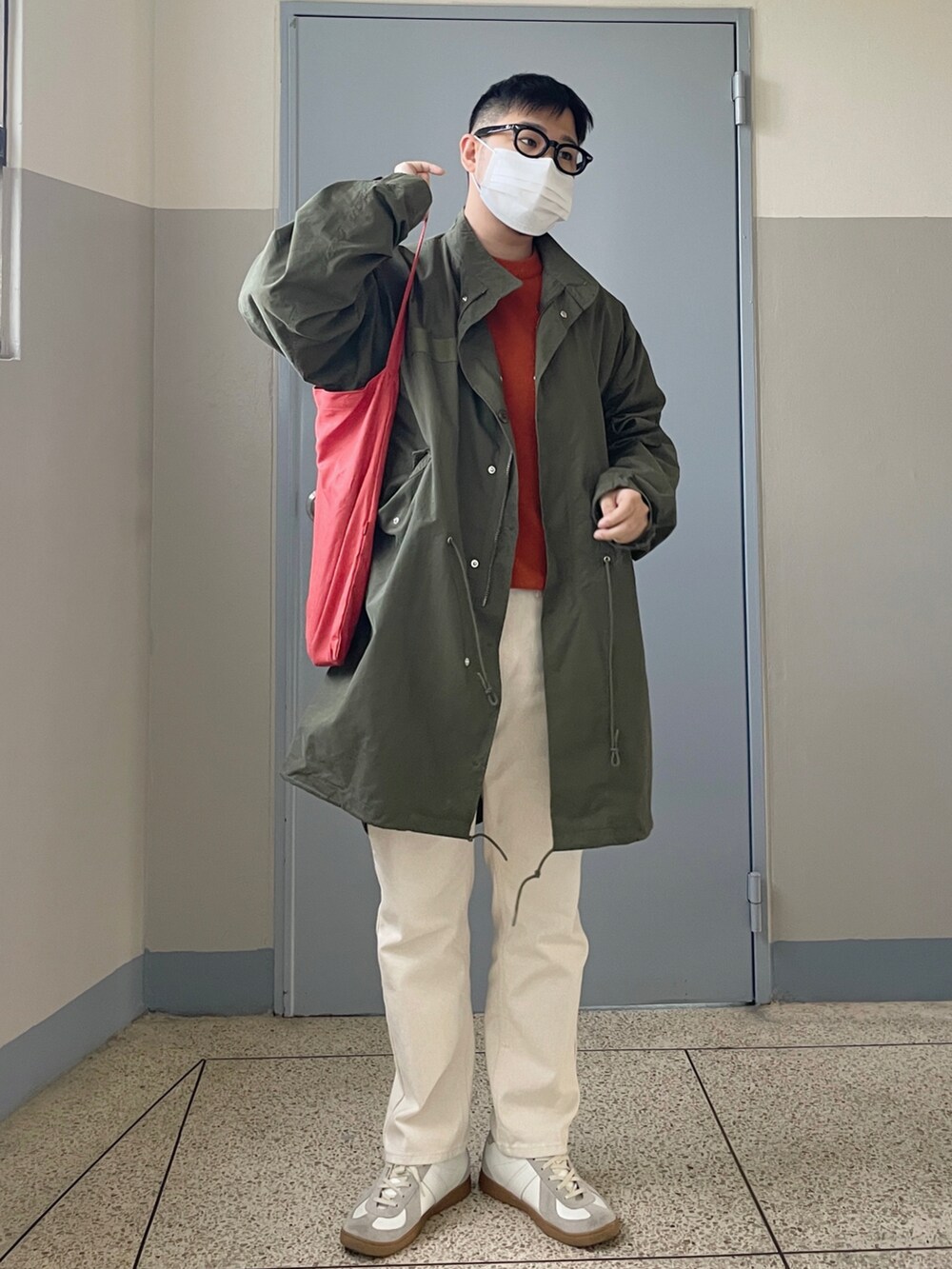 グリーン系のミリタリージャケット、オレンジ系のニット/セーター、ブルー系のシューズを着用したメンズの秋コーディネートの2枚目の写真