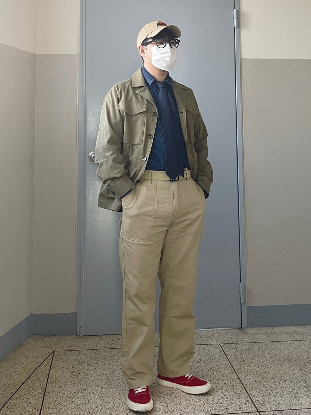レッド系のスニーカー、ベージュ系のチノパンツ、グリーン系のミリタリージャケットを着用したメンズの春コーディネートの2枚目の写真